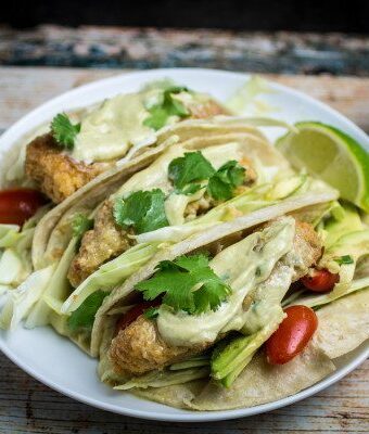 Crispy, juicy oven-fried fish smothered in a creamy, spicy avocado sauce and nestled in a warm tortilla. These Oven Fried Fish Tacos with Spicy Avocado Cream Sauce are simply perfect. Top with crunchy cabbage, cilantro, and a squeeze of fresh lime for an incredible flavor in this insanely easy-to-make dish!