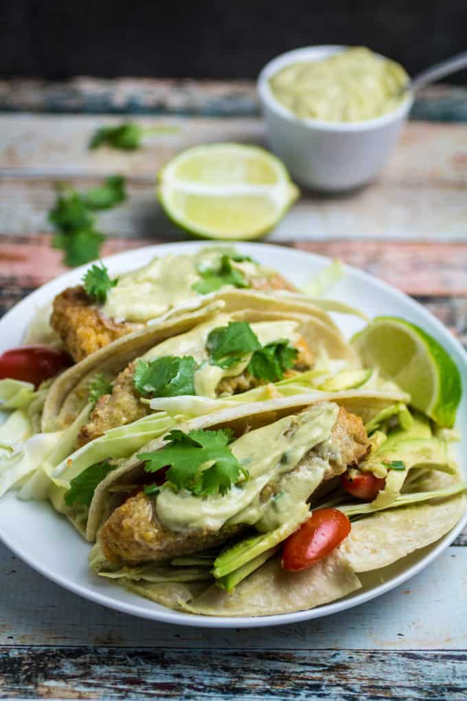 Crispy, juicy oven-fried fish smothered in a creamy, spicy avocado sauce and nestled in a warm tortilla. These Oven Fried Fish Tacos with Spicy Avocado Cream Sauce are simply perfect. Top with crunchy cabbage, cilantro, and a squeeze of fresh lime for an incredible flavor in this insanely easy-to-make dish!