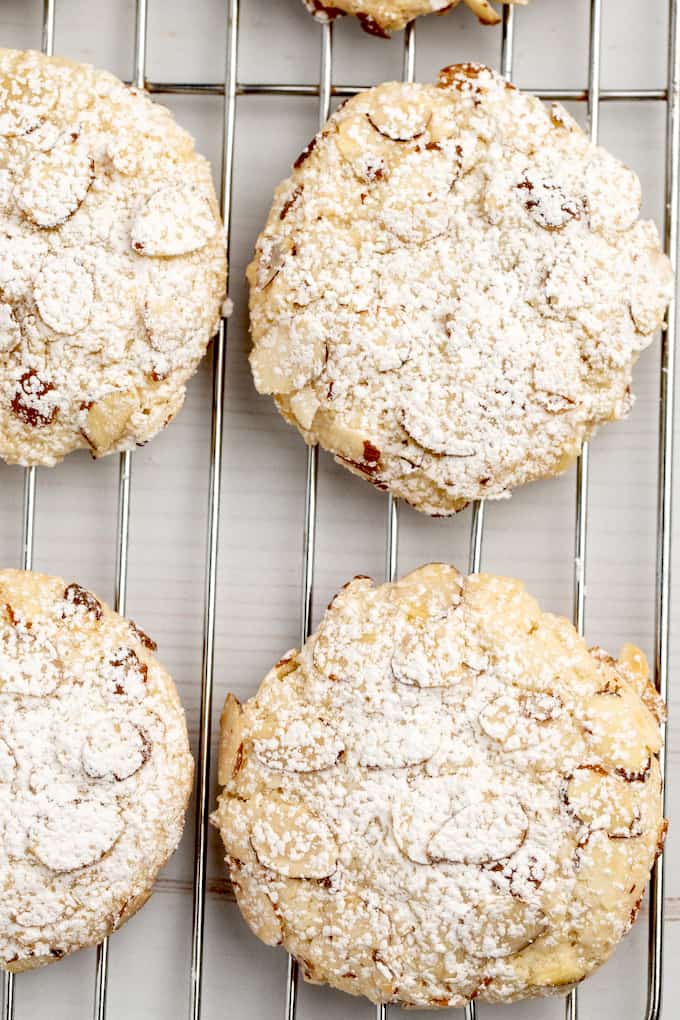 Downward view of almond paste cookie with sliced almonds and powdered sugar on a cooling rack