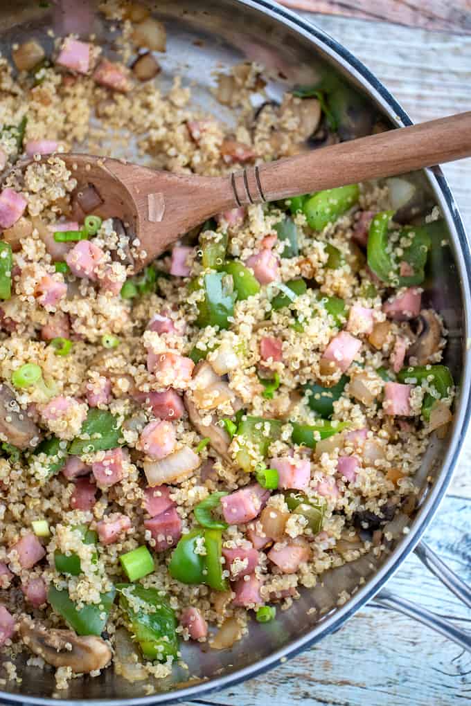 Skillet and wooden spoon with country quinoa bowl ham, veggies, and quinoa