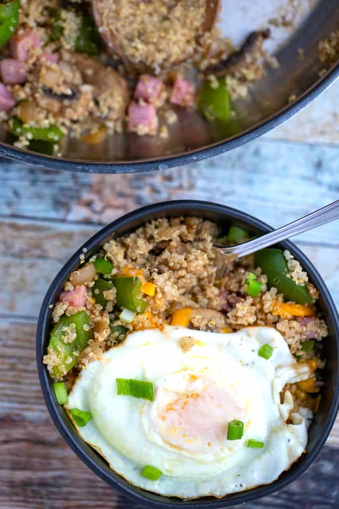 Bowl of country quinoa with an egg on top and skillet in the background