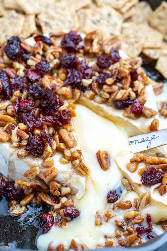 top view on pecan cranberry baked brie with melted cheese flowing out and surrounded by crackers