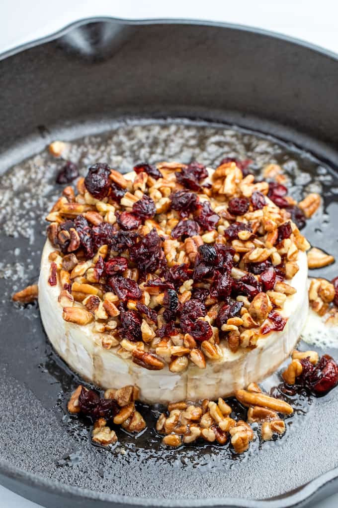 Top view of pecan cranberry baked brie in a cast iron skillet