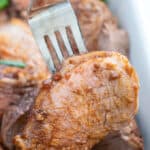 Pork tenderloin medallion on a fork with juicy liquid and raspberry balsamic marinade dripping from center