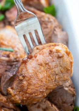 Pork tenderloin medallion on a fork with juicy liquid and raspberry balsamic marinade dripping from center