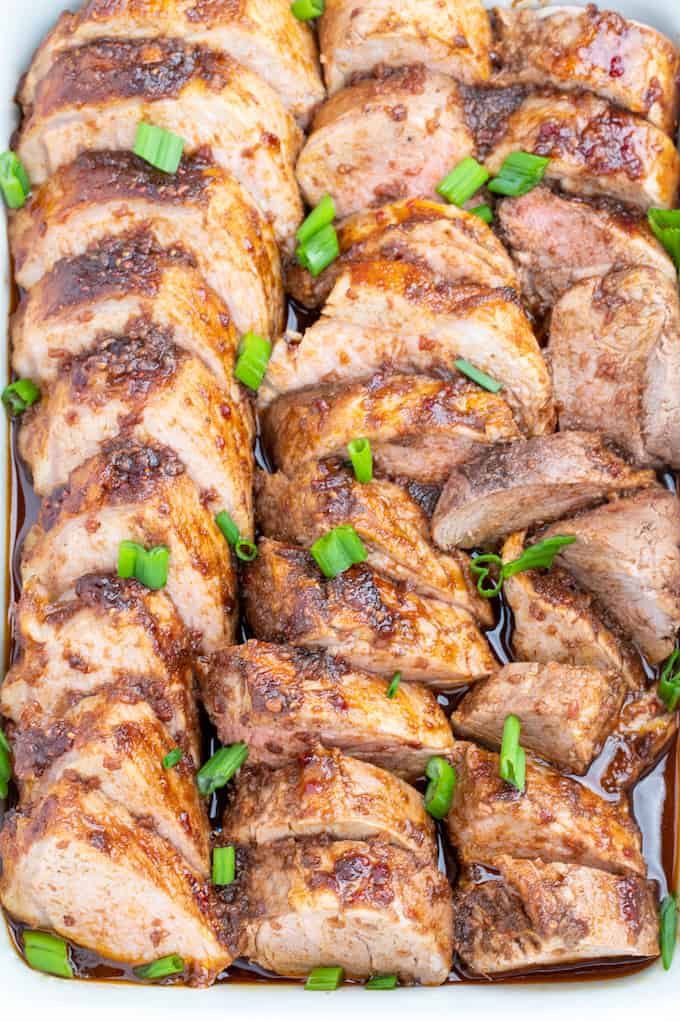 baking dish full of pork medallions with sear on top and cooked to perfection smothered in raspberry balsamic sauce and pork drippings