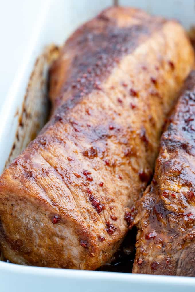 baking dish with two full pork loin roasts with sear on top and cooked to perfection smothered in raspberry balsamic sauce and pork drippings