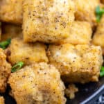 Closeup photo of crispy tofu cubes with seasoning and green onions