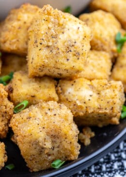 Closeup photo of crispy tofu cubes with seasoning and green onions