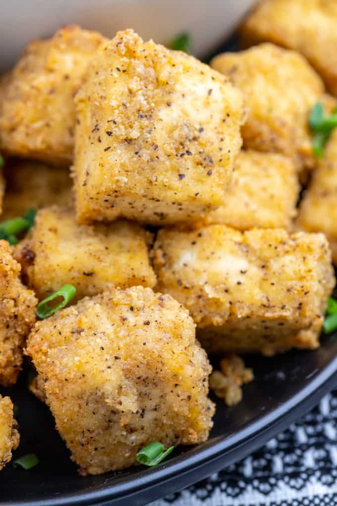 Closeup photo of crispy tofu cubes with seasoning and green onions