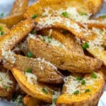 side view shot of air fryer potato wedges topped with parmesan and chopped chives