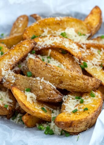 side view shot of air fryer potato wedges topped with parmesan and chopped chives