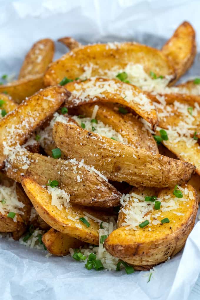 side view shot of air fryer potato wedges topped with parmesan and chopped chives