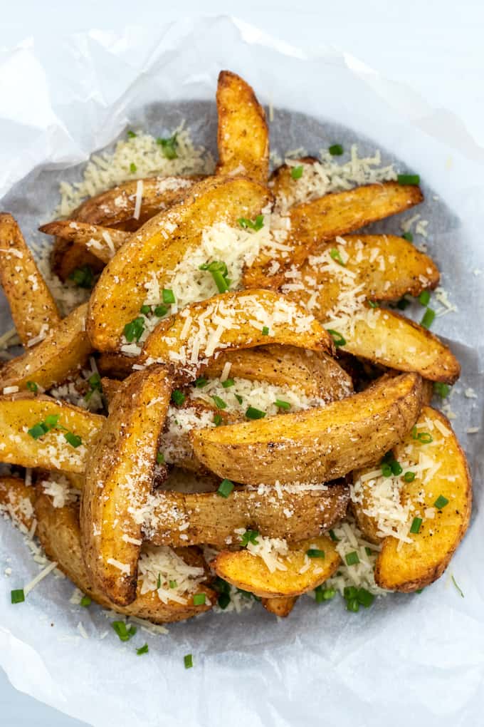 overhead shot of air fryer potato wedges topped with parmesan and chopped chives