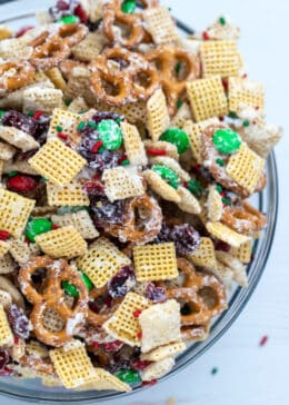 downward view of bowl with christmas chex mix made of pretzels, chex cereal, M&Ms, and dried cranberries coated in white chocolate