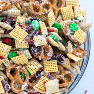 downward view of bowl with christmas chex mix made of pretzels, chex cereal, M&Ms, and dried cranberries coated in white chocolate