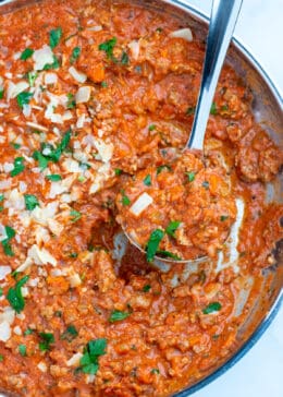 Turkey bolognese in a skillet with a spoon scooping sauce
