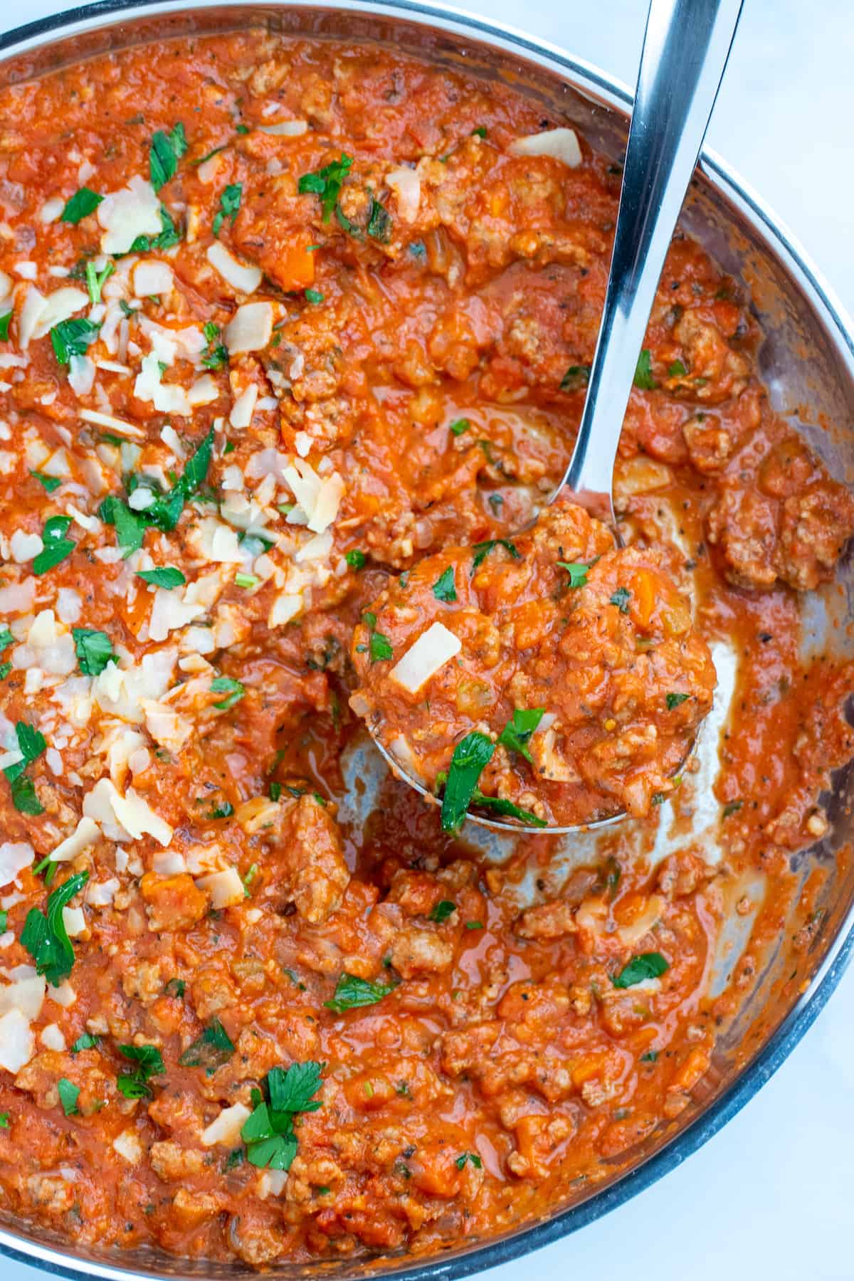 Turkey bolognese in a skillet with a spoon scooping sauce