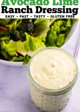 mason jar of avocado lime ranch dressing in front of a bowl of salad greens