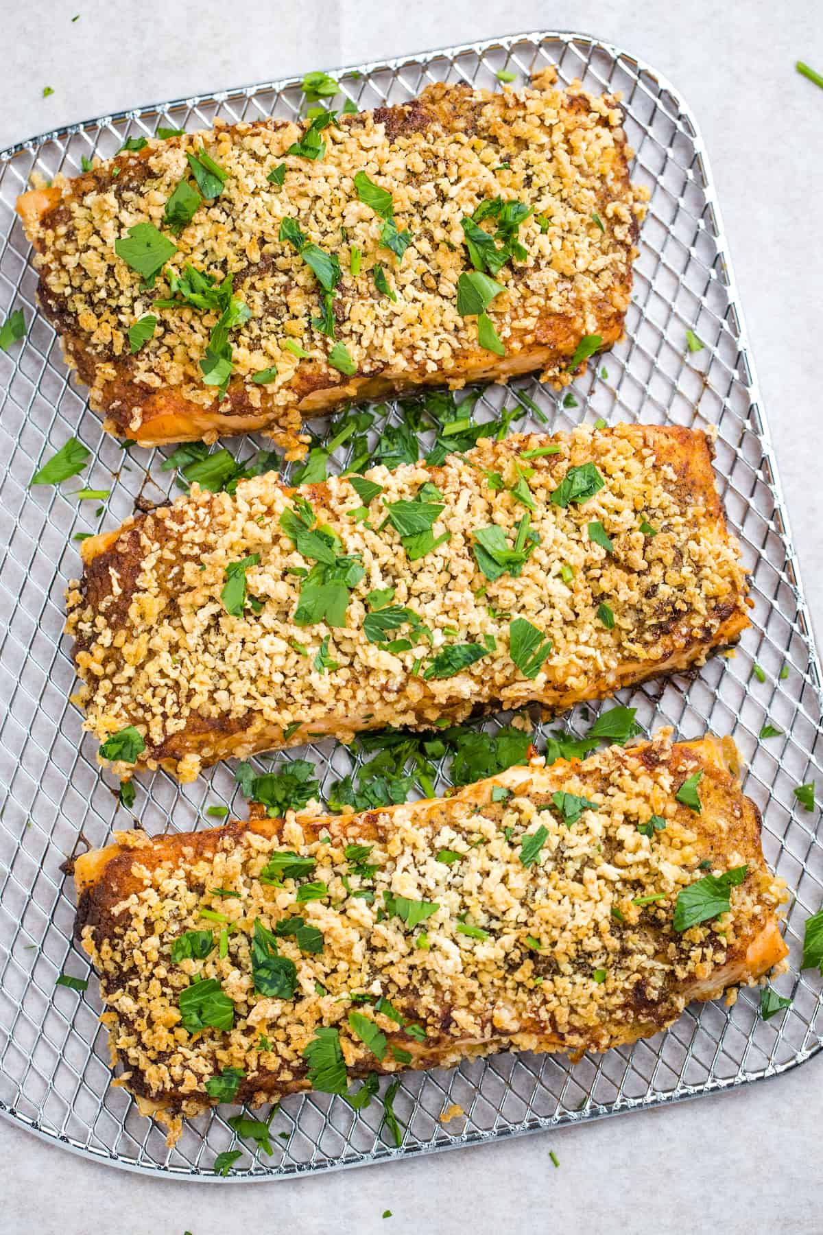 Close up of air fryer salmon with breadcrumb topping on an air fryer shelf.