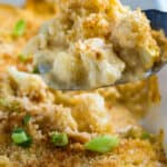 A spatula lifting cauliflower au gratin out of the baking dish.