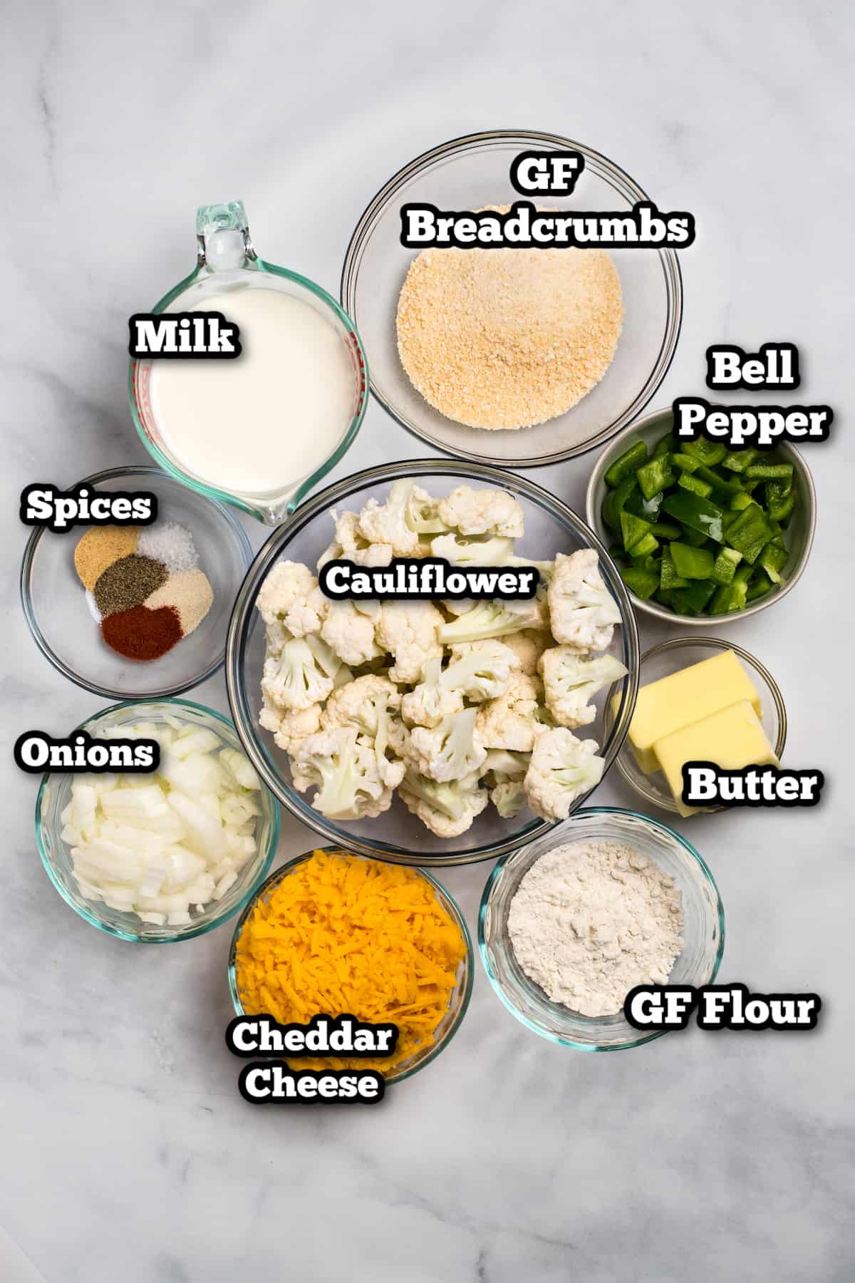 Ingredients for cauliflower au gratin in bowls on a marble table