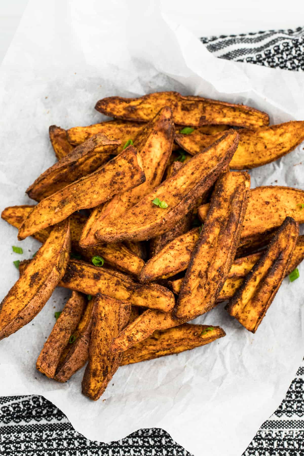 Air Fryer Sweet Potato Wedges sitting on top of parchment paper fully cooked.