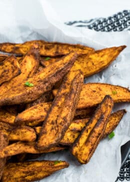 Fully cooked Air Fryer Sweet Potato Wedges sitting on top of parchment paper. They look crispy.