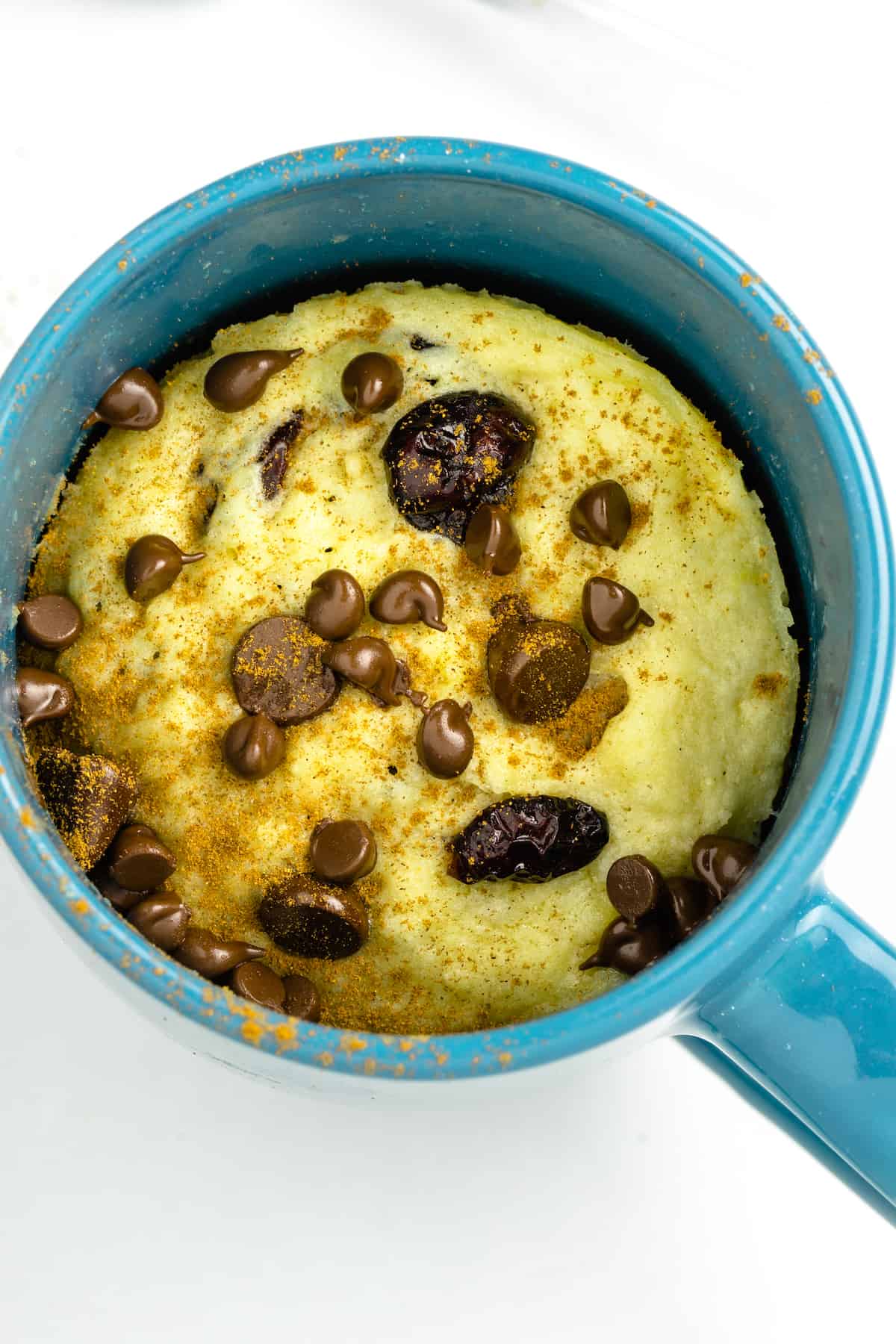 A chocolate chip mug cookie in a blue mug on the table.