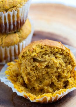 Pumpkin muffin sitting in a muffin liner on the table cut in half.