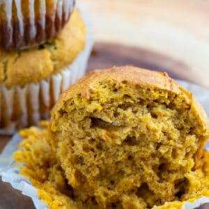 Pumpkin muffin sitting in a muffin liner on the table cut in half.