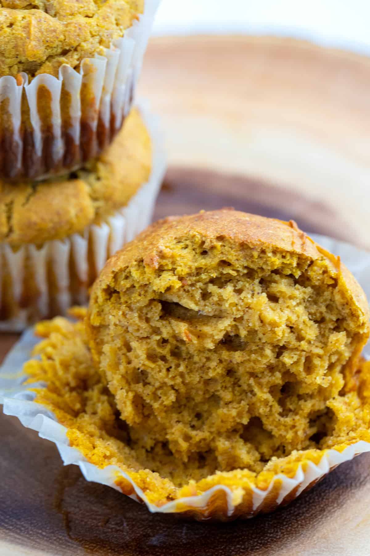 Pumpkin muffin in a muffin liner cut in half to reveal the fluffy center.