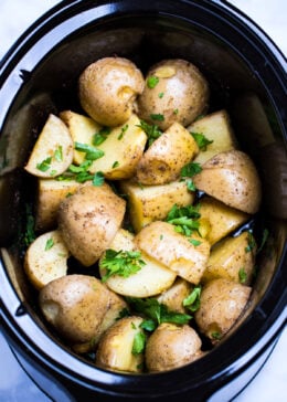 Gold potatoes in a slow cooker topped with fresh chopped parsley.