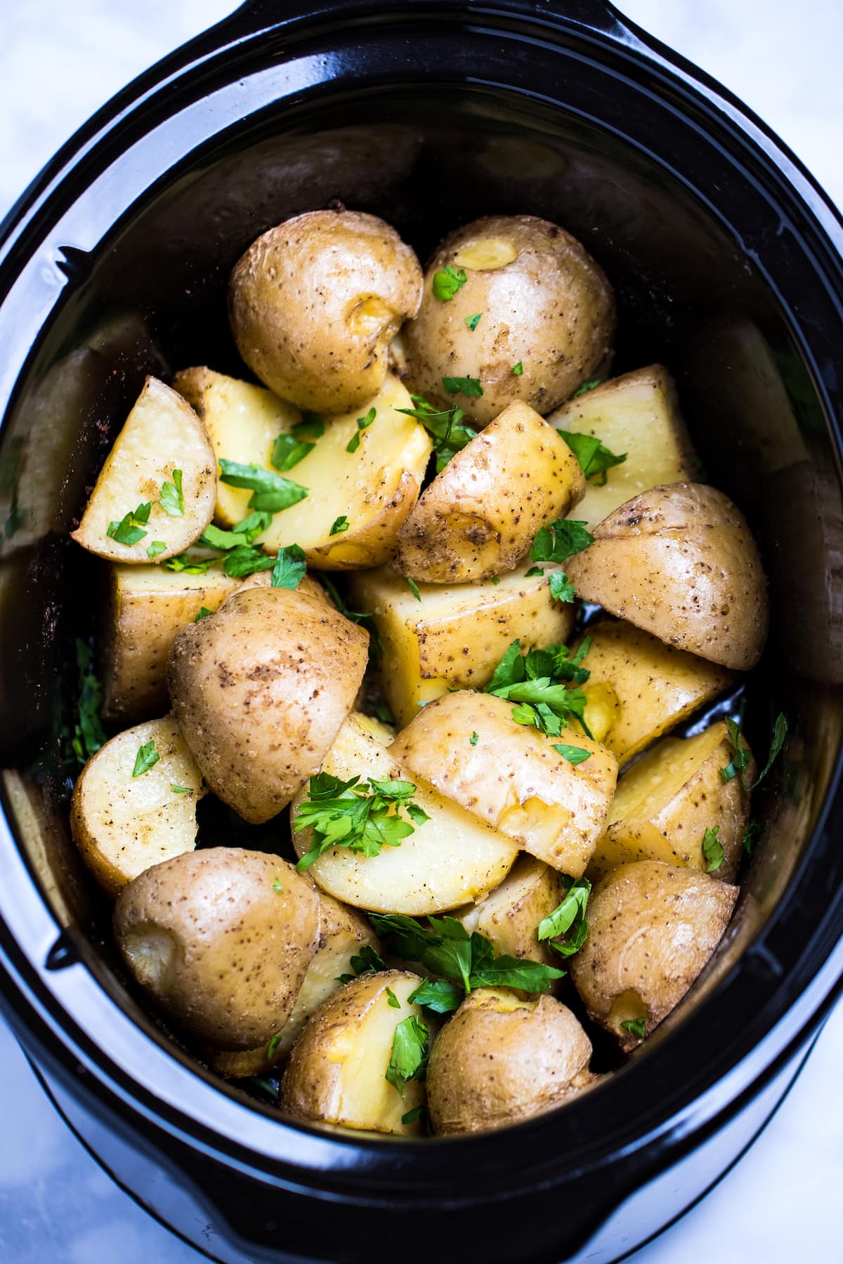 Gold potatoes in a slow cooker topped with fresh chopped parsley.