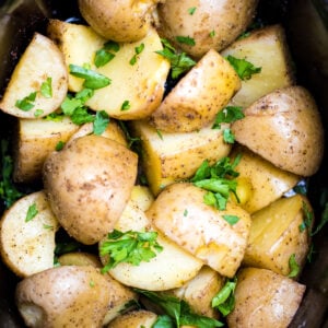 Gold potatoes in a slow cooker topped with fresh chopped parsley.