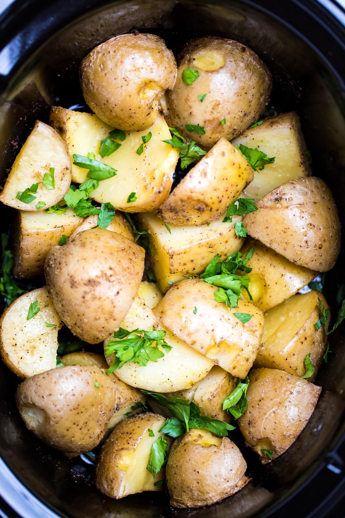 Gold potatoes in a slow cooker topped with fresh chopped parsley.