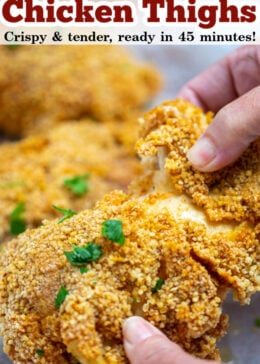 Pinterest pin of oven friend chicken thighs with a hand holding a crispy piece of chicken on top of parchment paper.