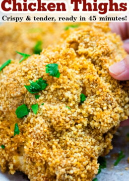 Pinterest pin of oven friend chicken thighs with a hand holding a crispy piece of chicken on top of parchment paper.