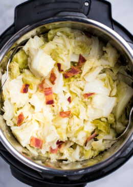 An instant pot full of cooked buttered cabbage topped with crispy bacon pieces.