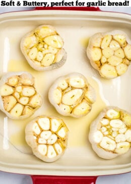 Raw garlic bulbs topped with olive oil sitting in a baking dish.