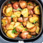 Air fryer basket full of red potatoes.