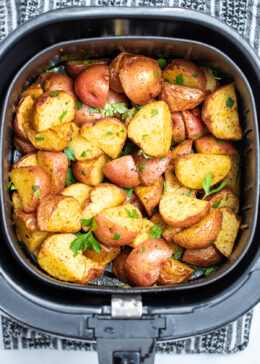 Air fryer basket full of red potatoes.