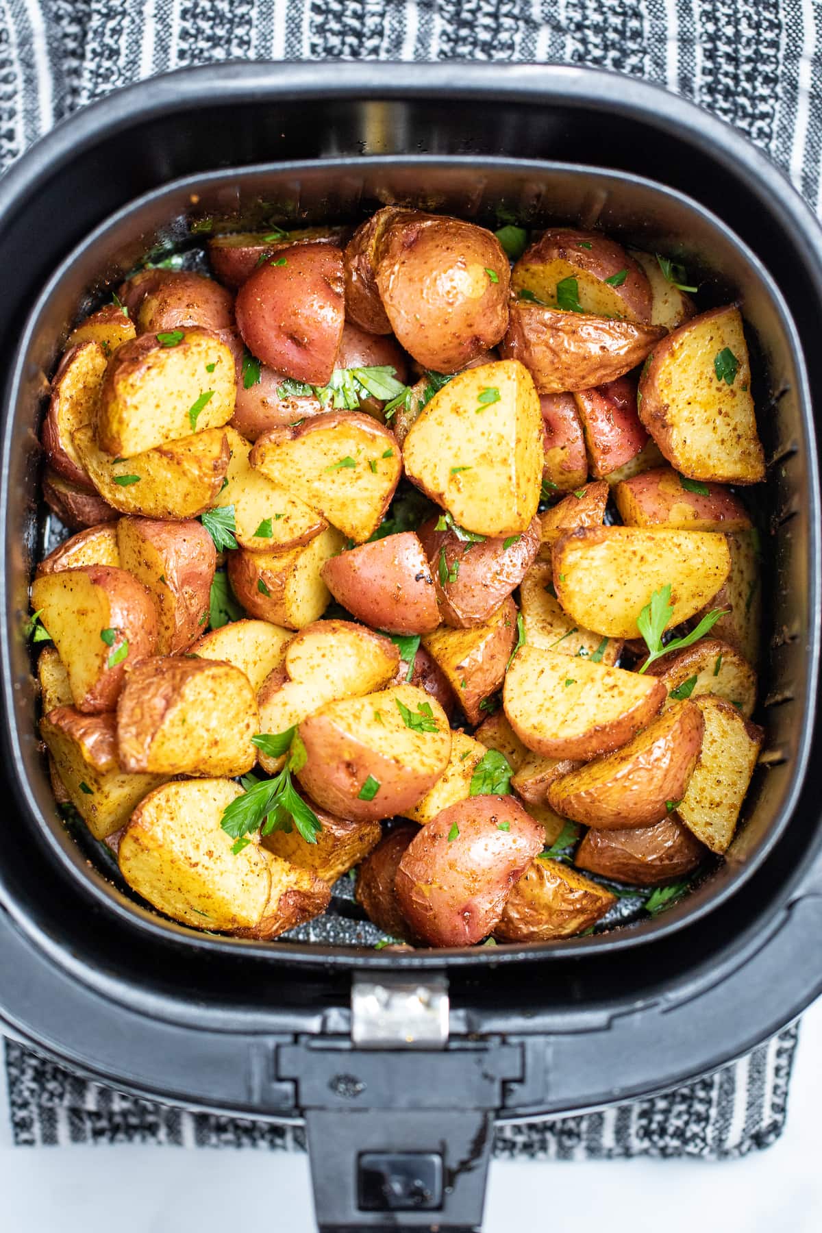 Air fryer basket full of red potatoes.