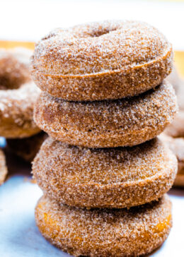 Four doughnuts stacked on top of each other coated in cinnamon sugar.