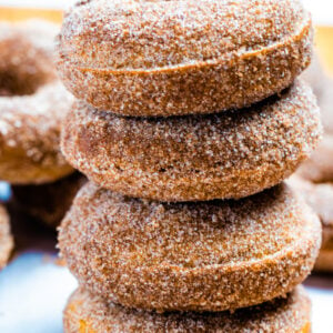 Four doughnuts stacked on top of each other coated in cinnamon sugar.