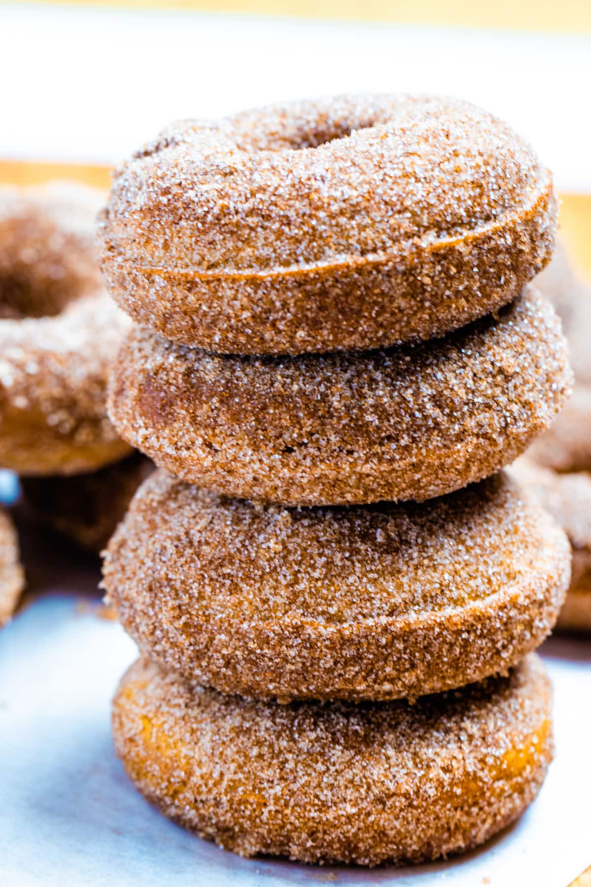 Four doughnuts stacked on top of each other coated in cinnamon sugar.