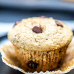 A banana muffin sitting in a muffin wrapper on a table.