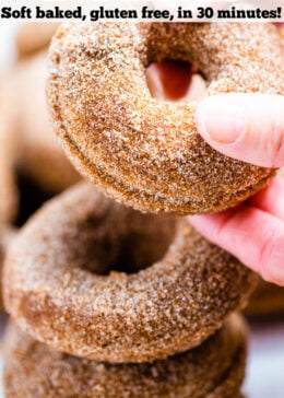 Pinterest pin with four doughnuts coated in cinnamon sugar stacked on top of each other and two hands holding the top doughnut.