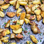 A sheet pan with a spatula lifting crispy roasted potatoes.