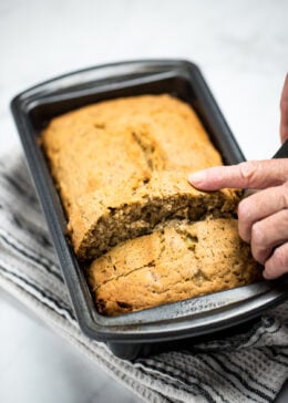 Pinterest pin with a loaf of banana bread in a bread pan on a table.